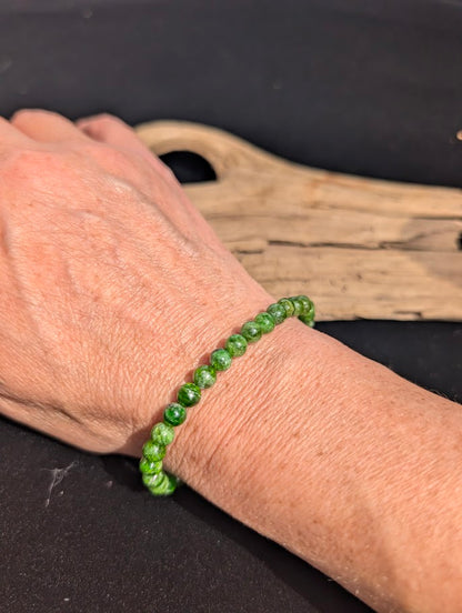 Natural sunlight on a 4mm vibrant green Chrome Diopside stretch bracelet worn on a wrist.