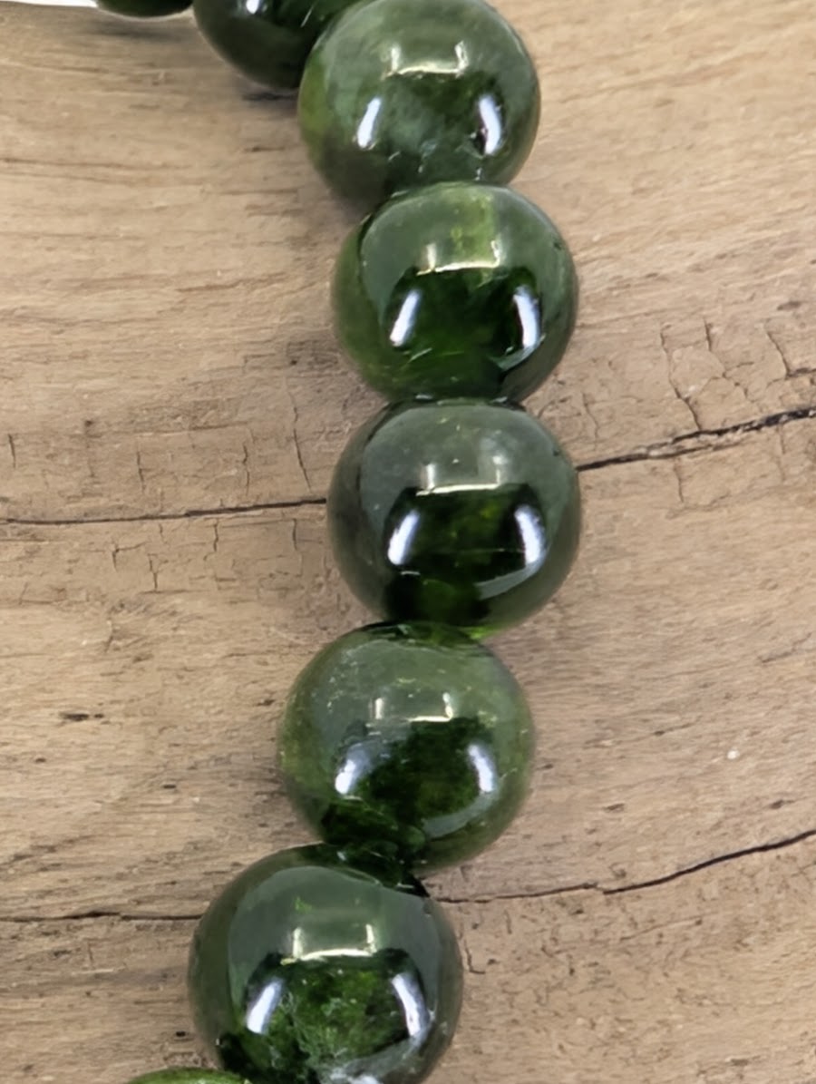 Macro view of Russian Chrome Diopside beads showing professional mirror-polish luster and deep internal glow.