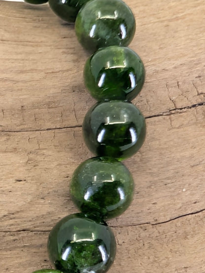 Macro view of Russian Chrome Diopside beads showing professional mirror-polish luster and deep internal glow.