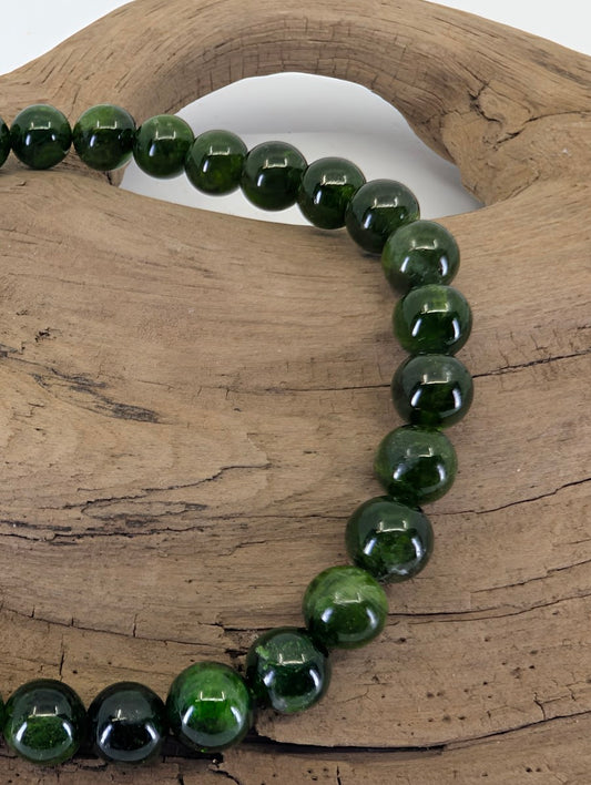 Close-up of 6.4mm Chrome Diopside beads highlighting the exceptional transparency and natural "Russian Emerald" hue.