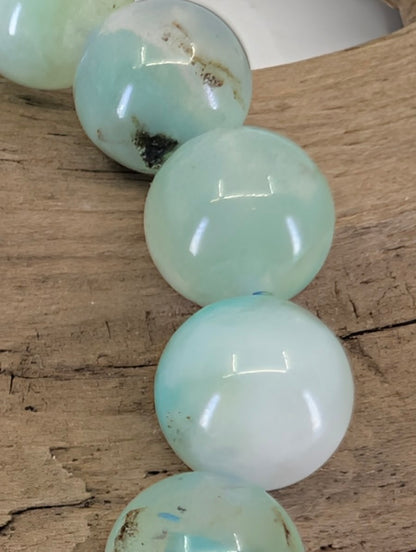 Macro view of Peruvian Chrysocolla beads showing high-gloss polish and authentic silica-rich mineral blooming.