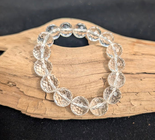 13mm faceted Clear Quartz beaded stretch bracelet resting on a driftwood display, showing high optical clarity.