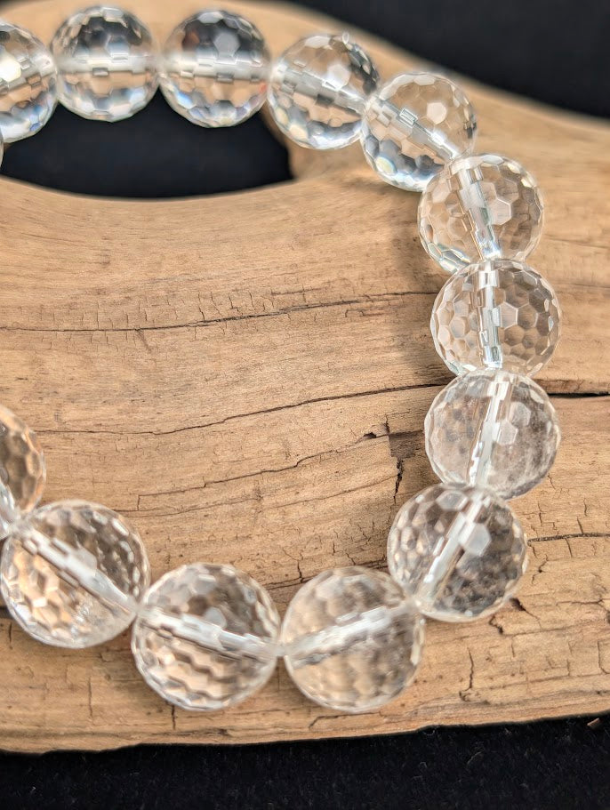 Macro close-up of 13mm faceted Clear Quartz beads highlighting geometric surface cuts and light refraction.