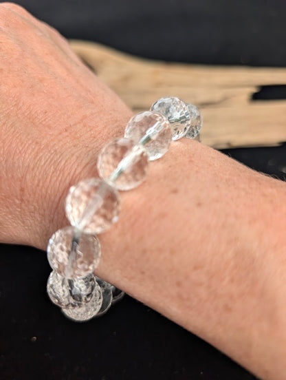 13mm faceted Clear Quartz beaded stretch bracelet worn on a wrist for size scale.