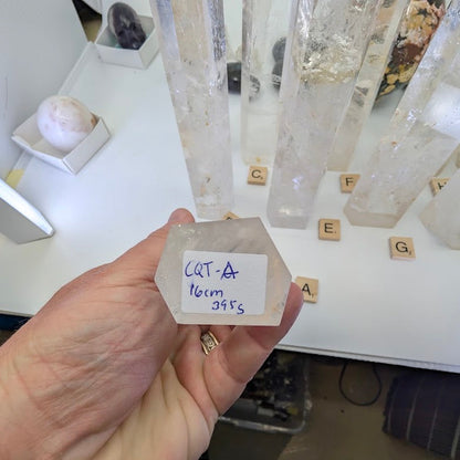 The flat, unpolished base of a 16cm Clear Quartz tower labeled CQT-A, 395g.