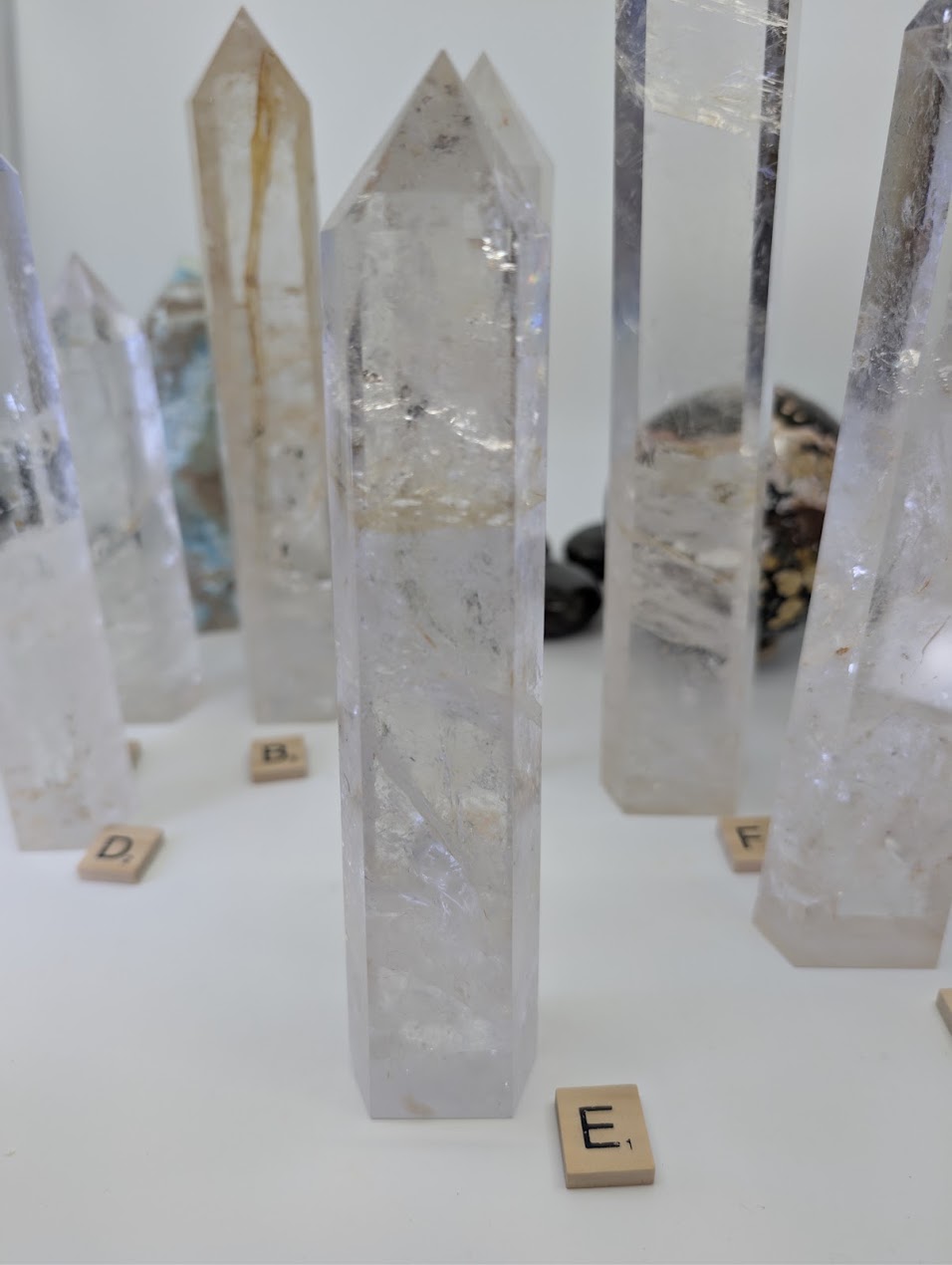Polished 20cm Clear Quartz obelisk (CQT-E) standing, showing a cloudy natural base leading to a highly transparent upper point.