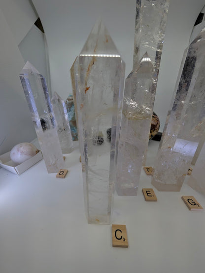 Polished 21cm Clear Quartz tower (CQT-C) displaying striking internal fracture planes that create natural rainbow iridescence.