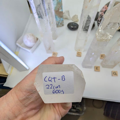 The flat, hexagonal base of a 22cm Clear Quartz obelisk labeled CQT-B, 600g.