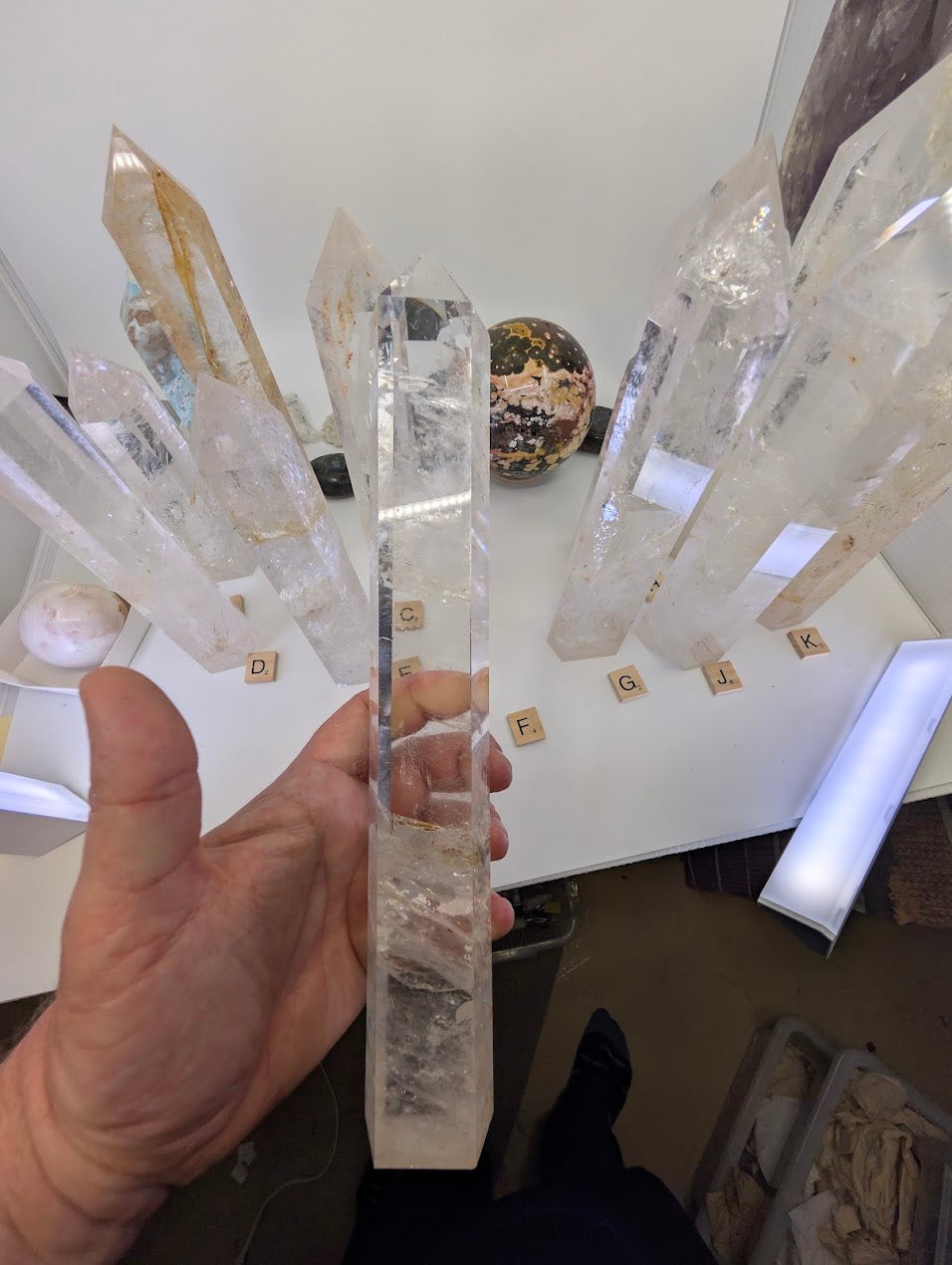 Hand holding the large 31cm Clear Quartz obelisk (CQT-F) demonstrating its substantial size and clear apex.