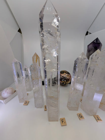 A massive 31cm polished Clear Quartz tower (CQT-F) towering above others, showing layered internal veiling.