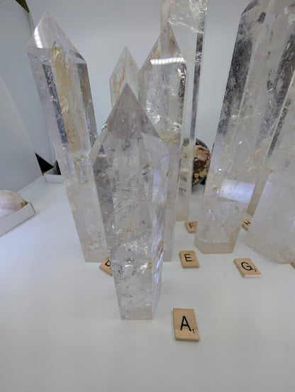 Close-up view of a collection of polished Clear Quartz obelisks showing natural internal fracture planes and light refraction.