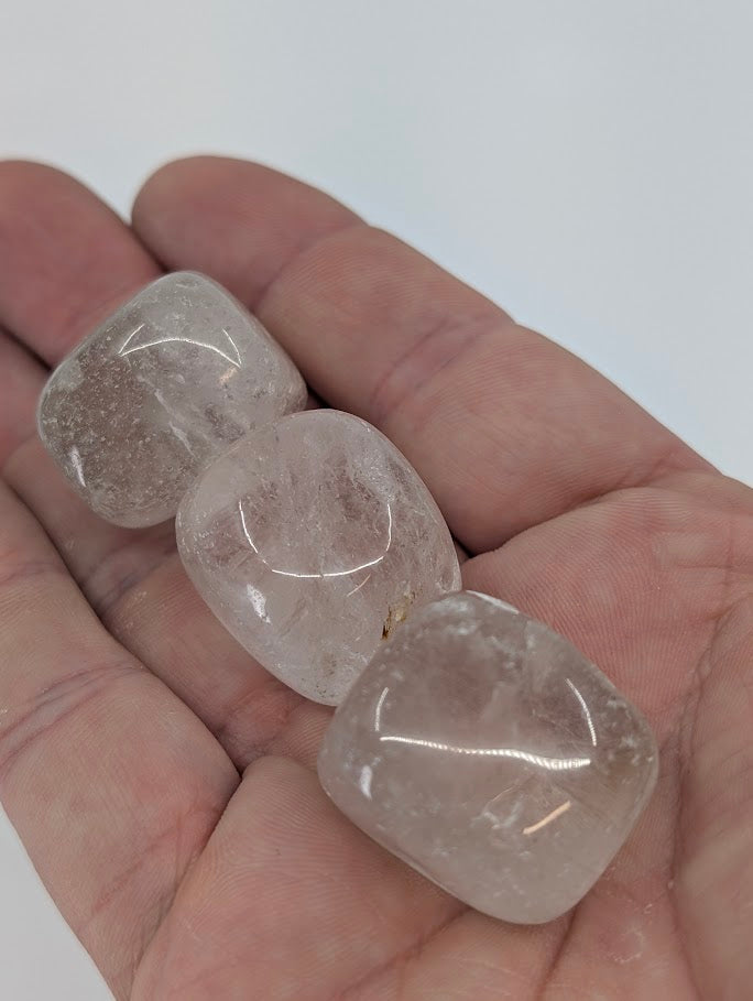 Clear Quartz tumbled stones in hand for size reference
