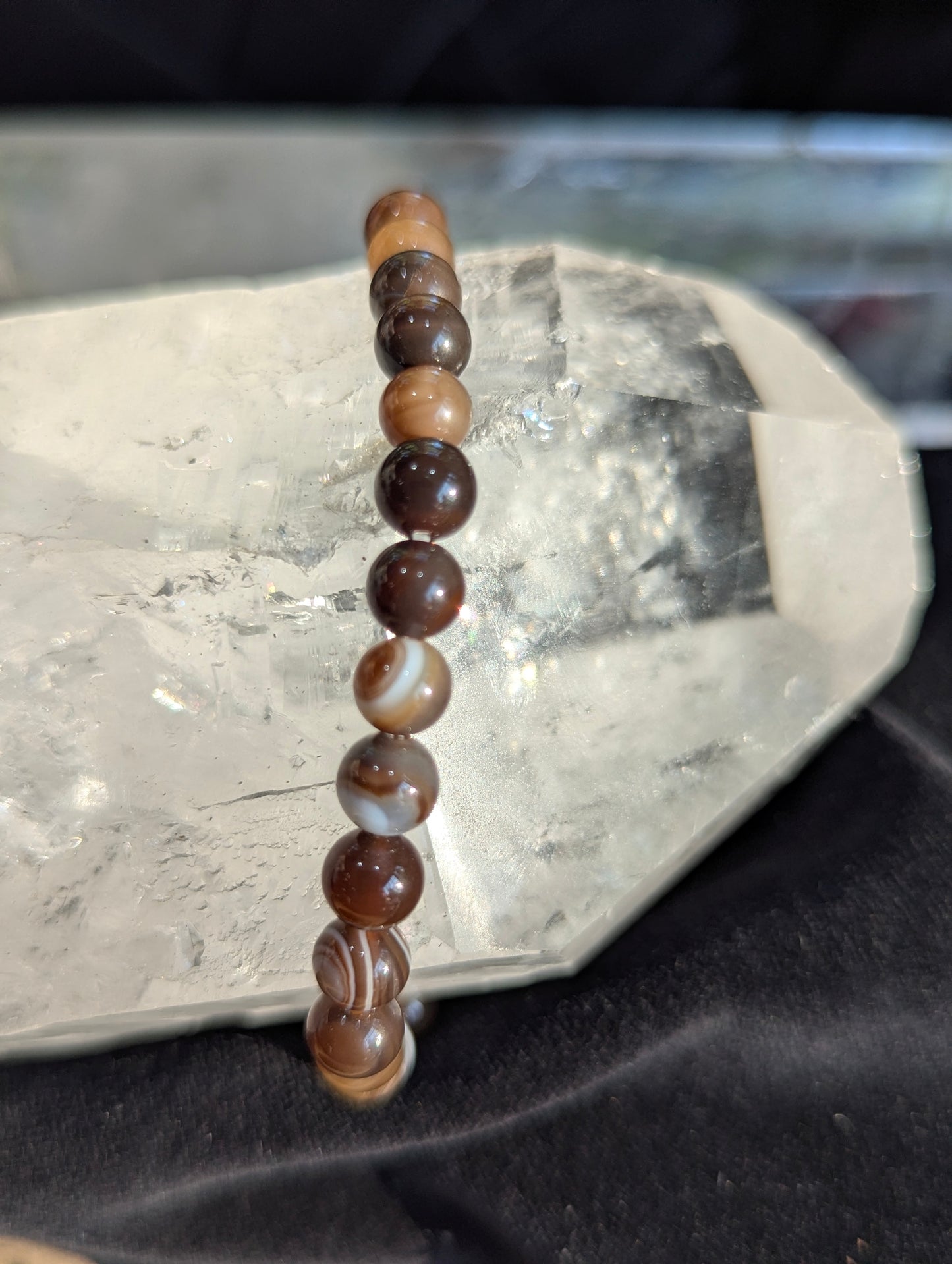 Hand-held view of a 6mm Coffee Agate beaded stretch bracelet to demonstrate dimensional scale, bead calibration, and the rich, un-stabilized translucent mocha colour profile.