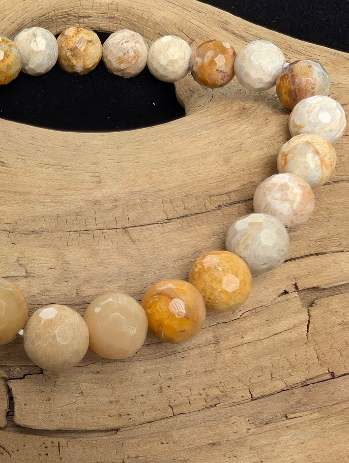 Macro close-up of 8mm faceted Coral Jade beads highlighting geometric surface cuts and natural floral fossilized coral polyps.