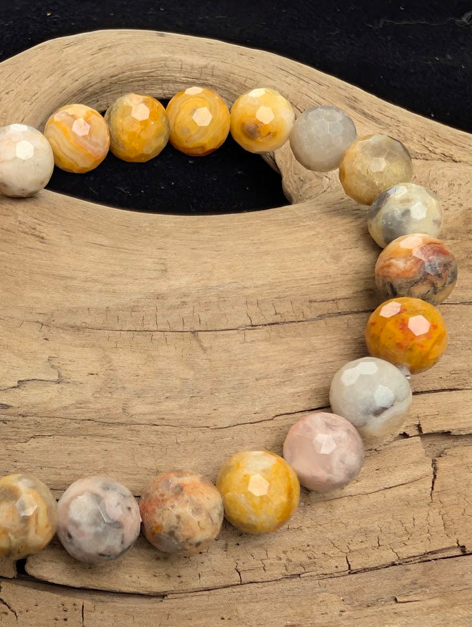 Macro close-up of 8mm faceted Crazy Lace Agate beads highlighting the geometric cut and the intricate natural lace patterns within the chalcedony.