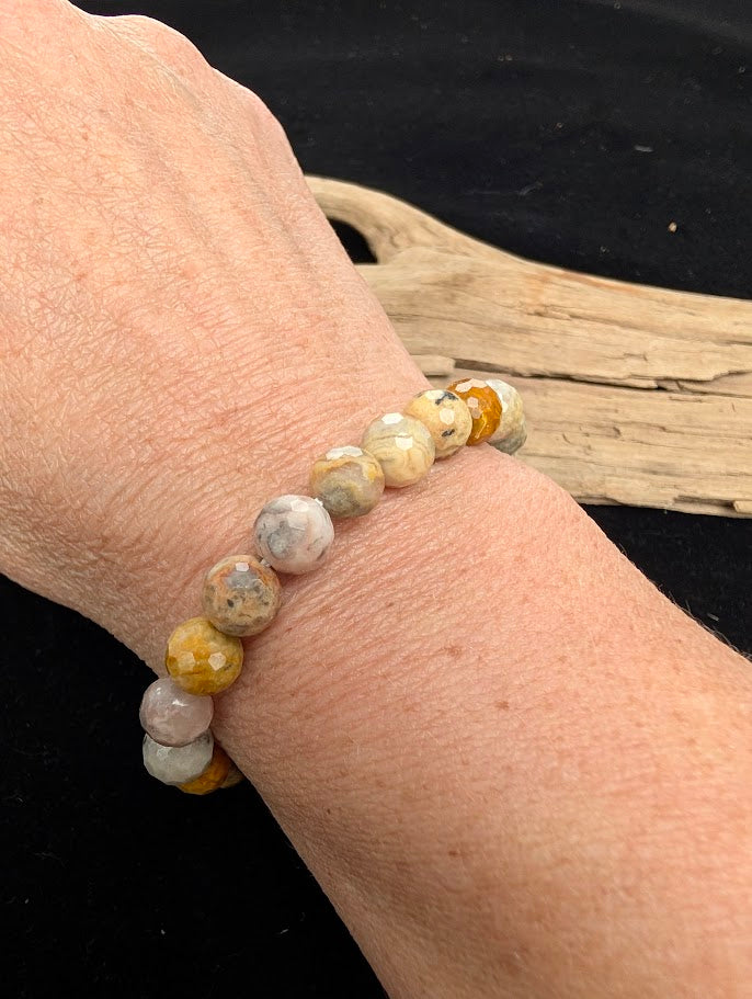 8mm faceted Crazy Lace Agate beaded stretch bracelet worn on a wrist for size scale.