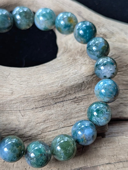 Close-up view of 10mm Dark Moss Agate beads displaying striking clarity and organic forest-like patterns.