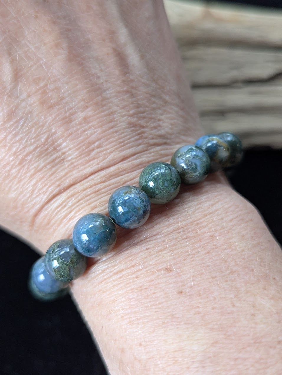10mm Dark Moss Agate bracelet worn on the wrist, emphasizing its substantial profile and rich earthy color palette.