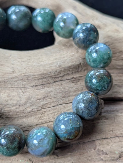 Macro shot of 12mm Dark Moss Agate beads revealing expansive dendritic patterns and high-gloss polish.
