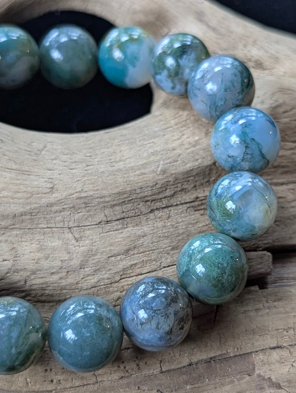 Close-up macro view of 13mm Dark Moss Agate beads showing bold, expansive mossy inclusions and exceptional translucency.