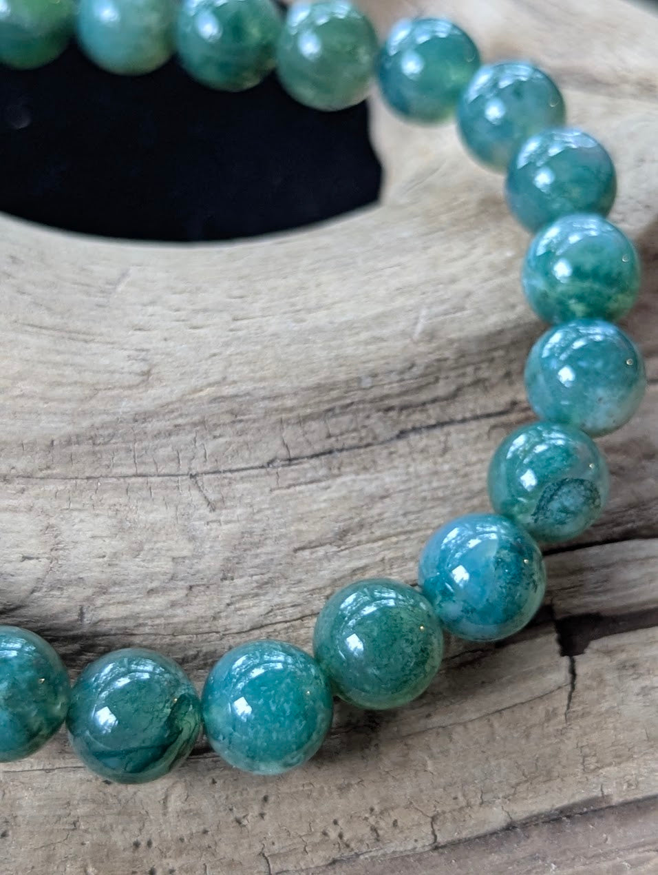 Close-up macro view of an 8mm Dark Moss Agate bead strand highlighting deep emerald-green moss inclusions and high-polish finish.