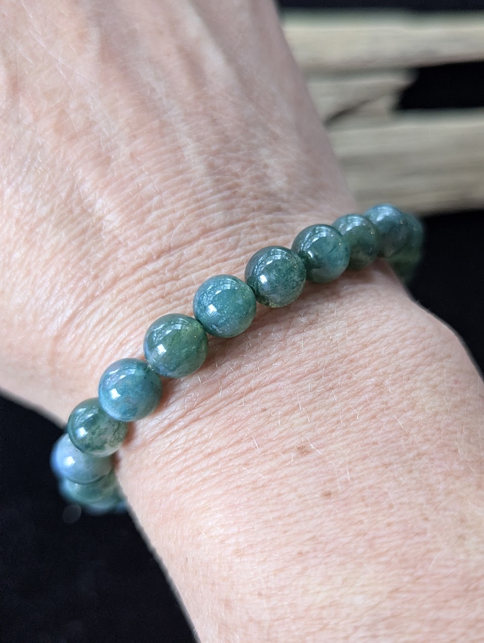 8mm Dark Moss Agate gemstone bracelet worn on a wrist, demonstrating scale and natural green aesthetic.