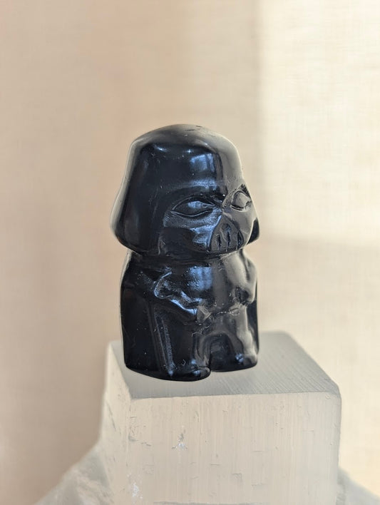A 3cm Darth Vader carved from natural Black Obsidian displayed on a white crystal base.