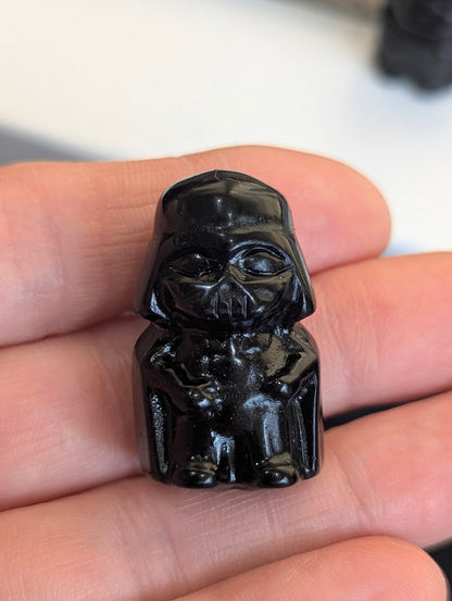Front view of a tiny 3cm Black Obsidian Darth Vader carving held in a hand.