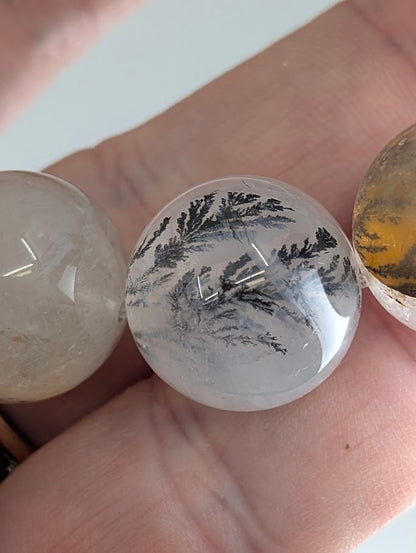 Macro photo of dendritic quartz beads with detailed manganese oxide inclusions.