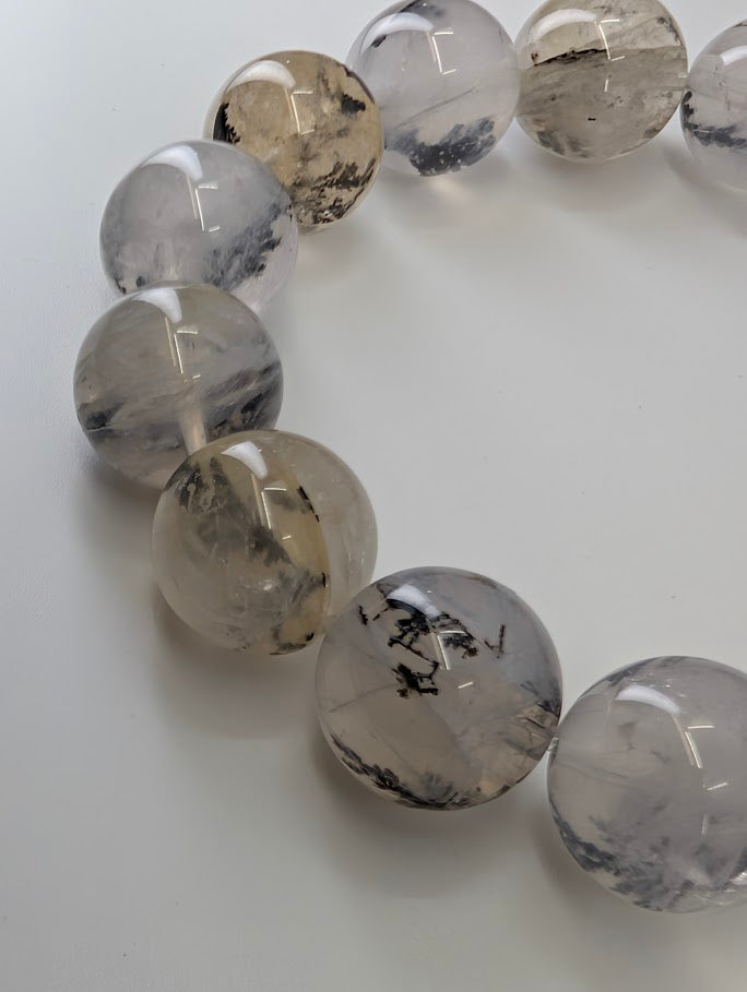 Close-up of 15mm dendritic quartz bracelet highlighting high-clarity beads with bold dendrite structures.