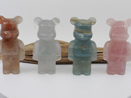 A collection of four designer bear carvings in Fire Quartz, Rose Quartz, Blue Onyx, and Fluorite.