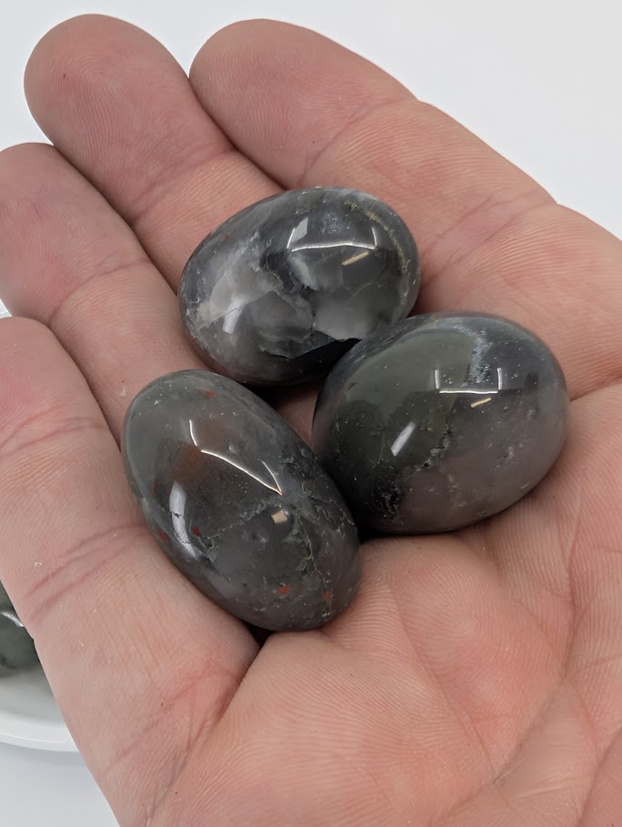 Dragon Blood Jasper tumbled stones shown in hand for scale