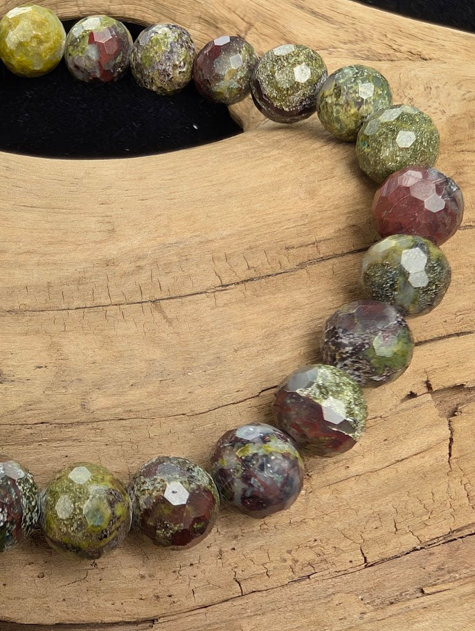 Macro close-up of 8mm faceted Dragon Blood Stone beads highlighting geometric surface cuts and natural green and red mottled patterns.