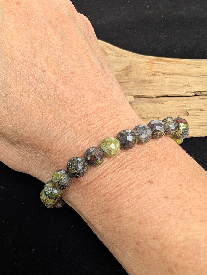 8mm faceted Dragon Blood Stone beaded stretch bracelet worn on a wrist for size scale.