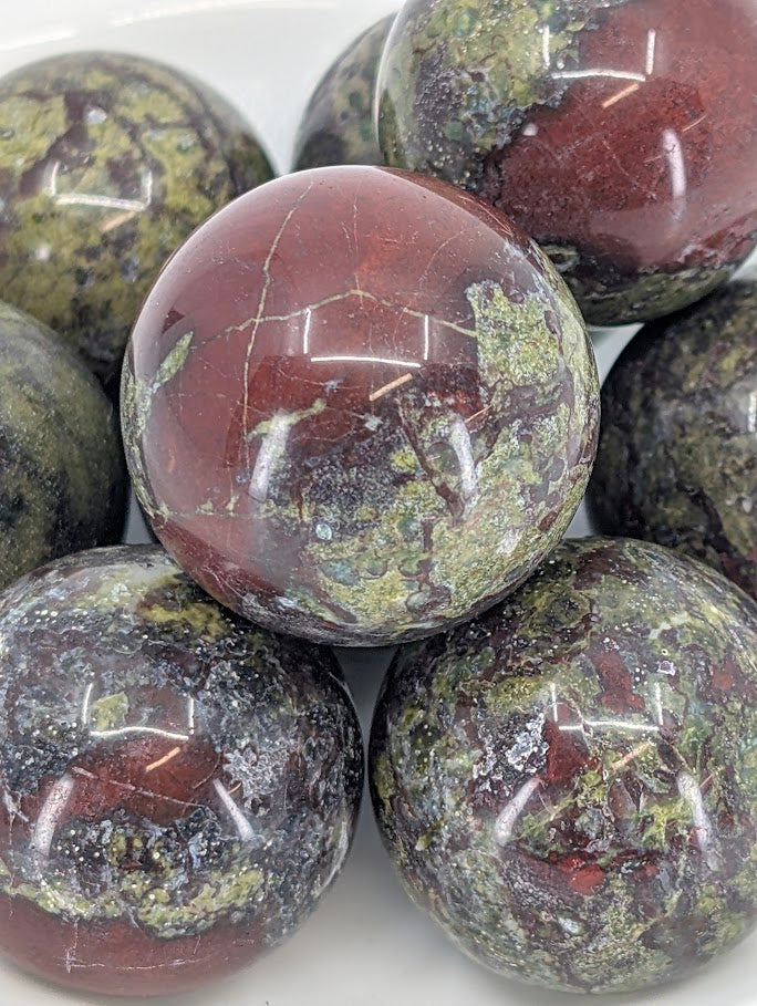 Close-up of Dragon Blood Stone sphere with crimson patches on dark green