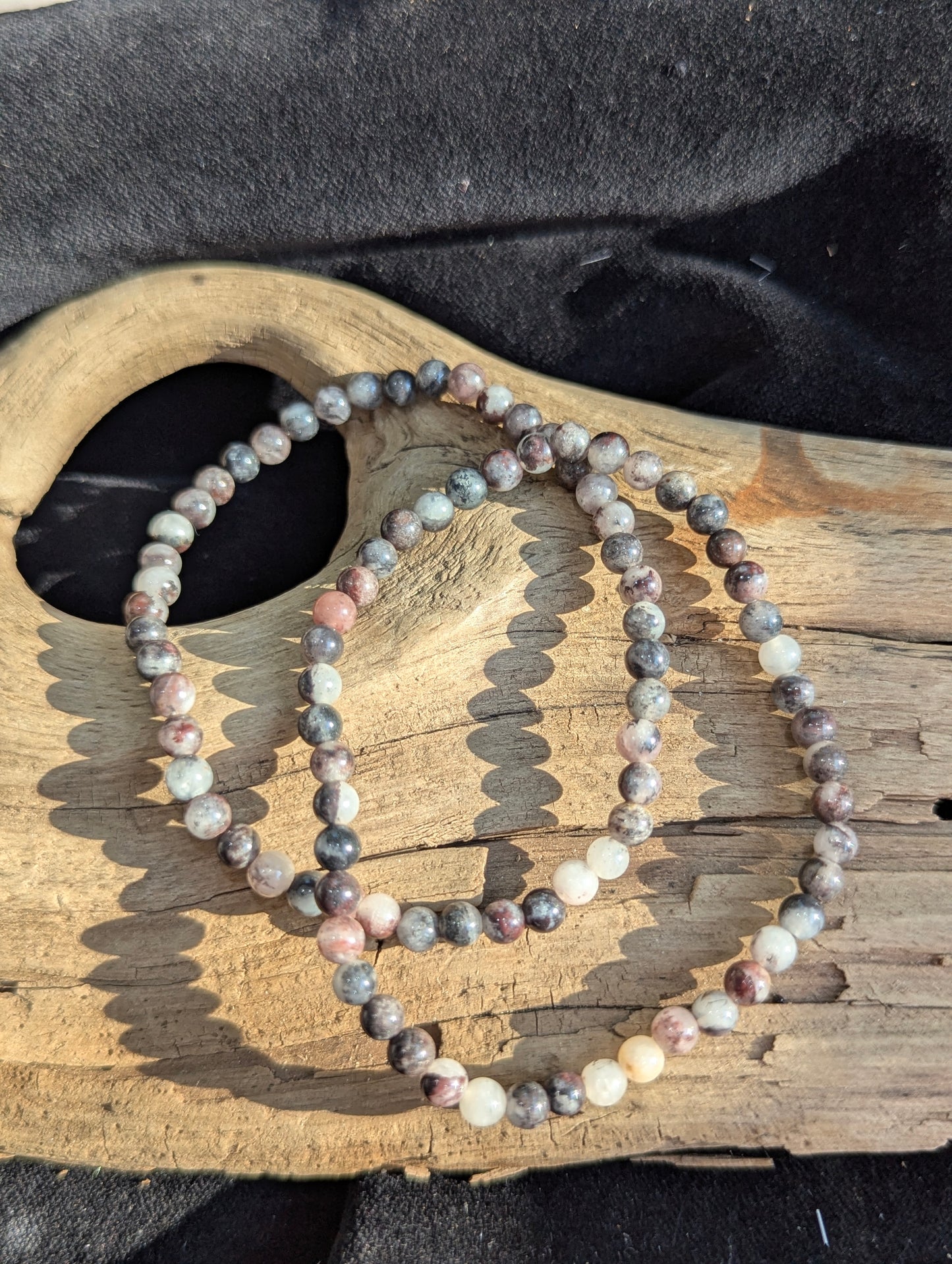 An all-natural 4mm Dragon Bloodstone beaded stretch bracelet resting on a neutral presentation surface, showcasing polished lime-green epidote and crimson red jasper inclusions.