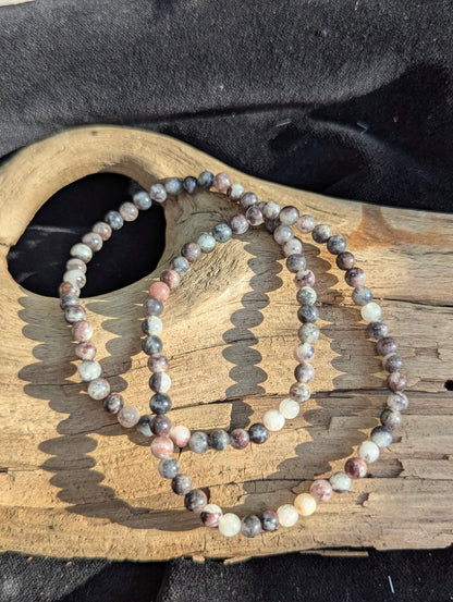 An all-natural 4mm Dragon Bloodstone beaded stretch bracelet resting on a neutral presentation surface, showcasing polished lime-green epidote and crimson red jasper inclusions.