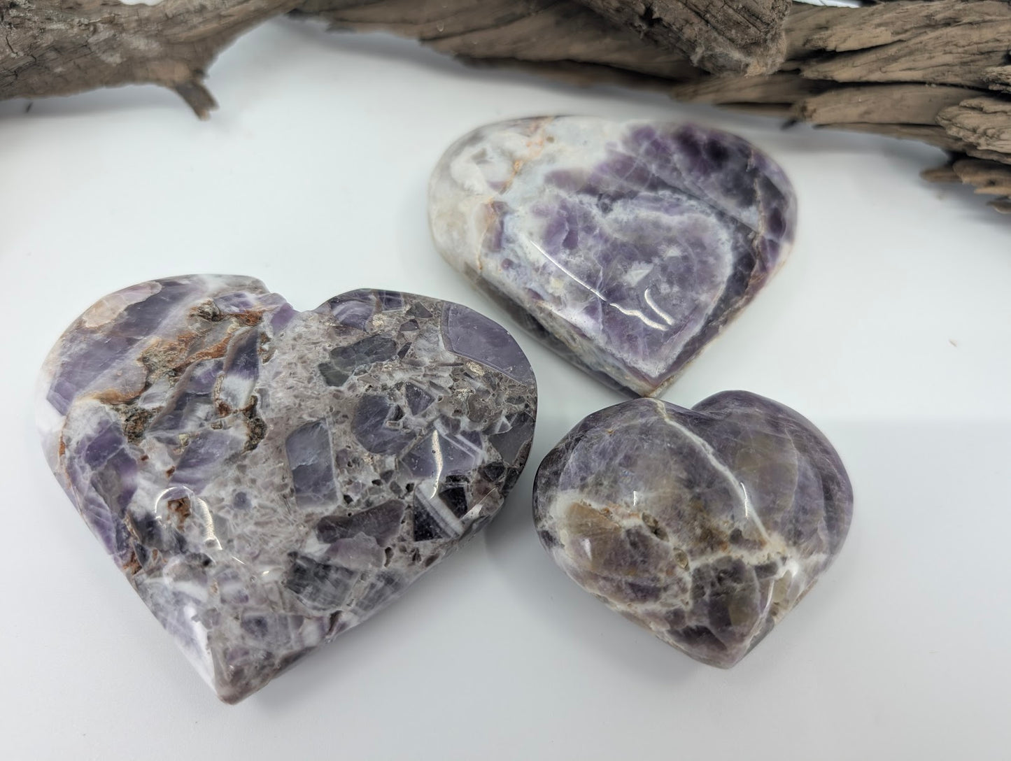 Group of three Dream Amethyst hearts showing white chevron banding.