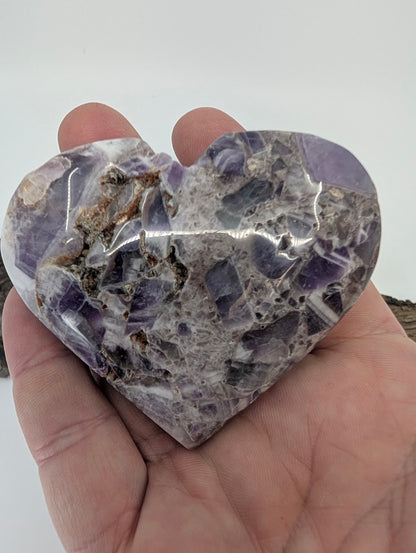 Hand holding a large purple Dream Amethyst heart showing polished texture.