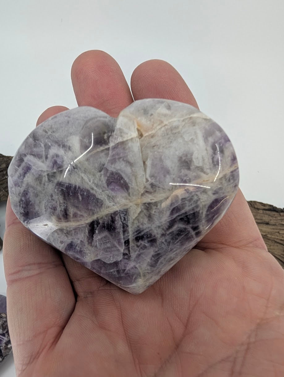 Hand holding a medium purple Dream Amethyst heart showing polished texture.