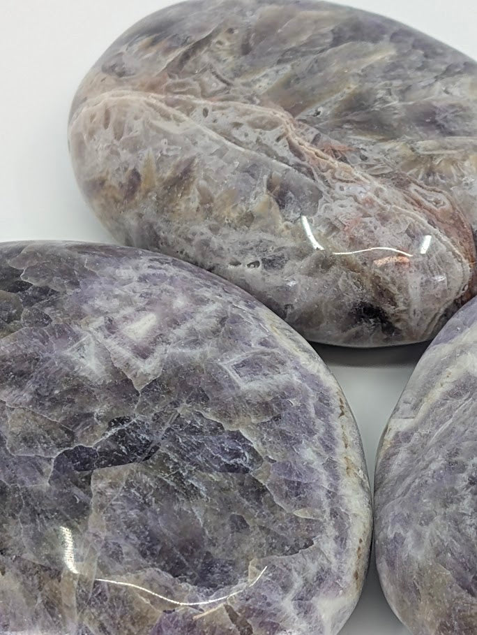 Close-up of Dream Amethyst Palm Stone highlighting natural chevron banding and quartz layers