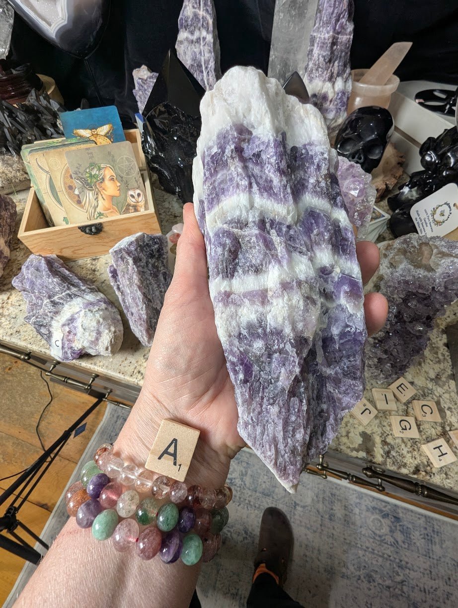 Hand holding a large raw Dream Amethyst chunk, showing dramatic chevron banding and robust crystal structure.