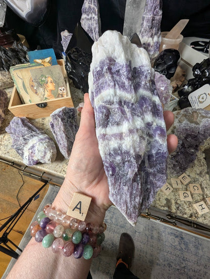 Hand holding a large raw Dream Amethyst chunk, showing dramatic chevron banding and robust crystal structure.