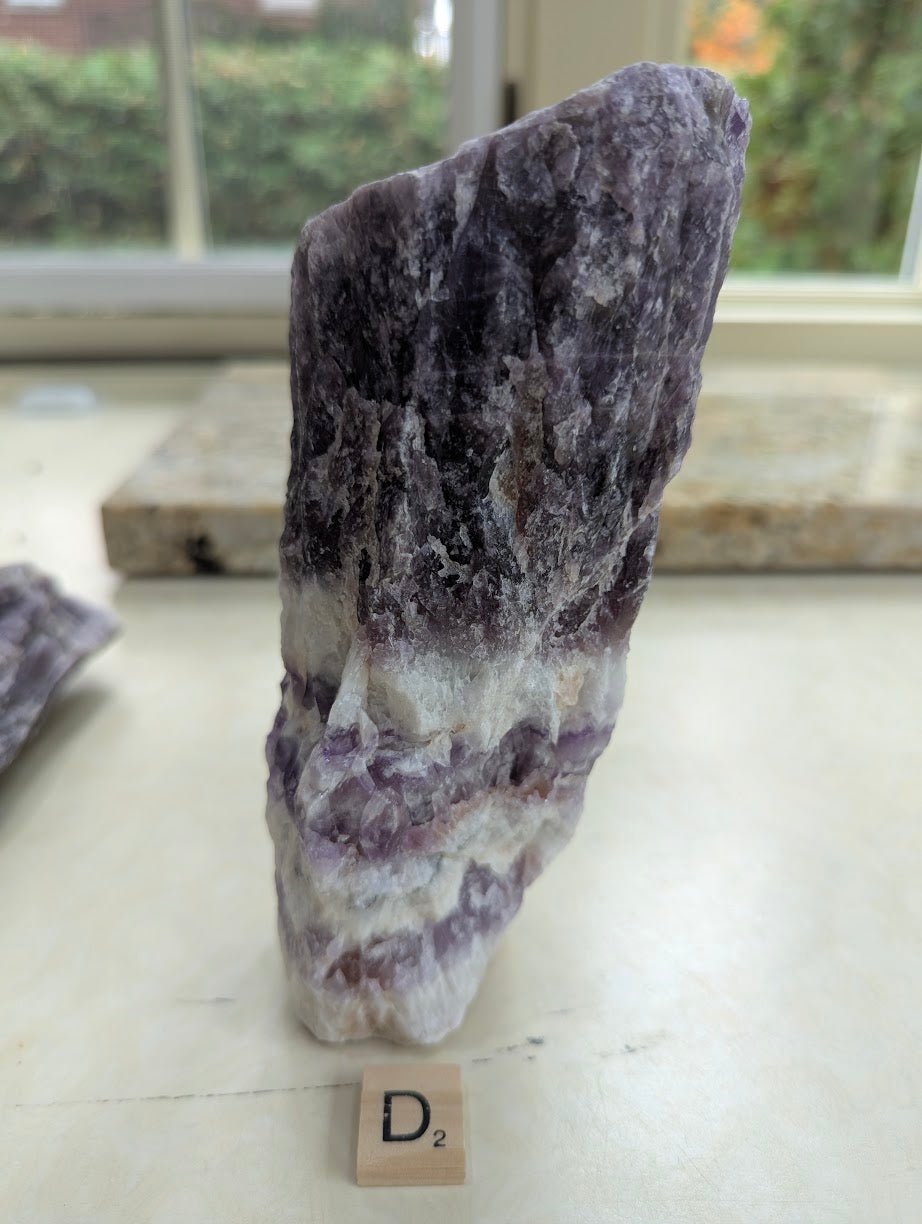 Standing raw Dream Amethyst specimen, showing intense dark purple hues transitioning into milky white quartz at the base.