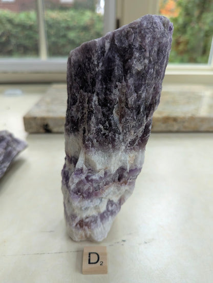 Standing raw Dream Amethyst specimen, showing intense dark purple hues transitioning into milky white quartz at the base.