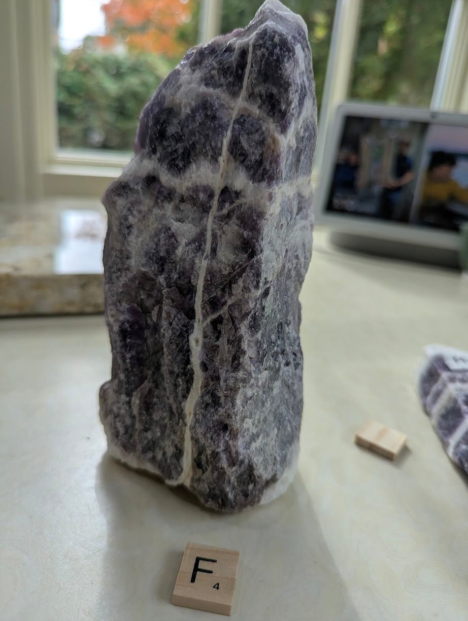 Standing raw Dream Amethyst specimen, showing vertical white quartz veins intersecting dark purple mineral.
