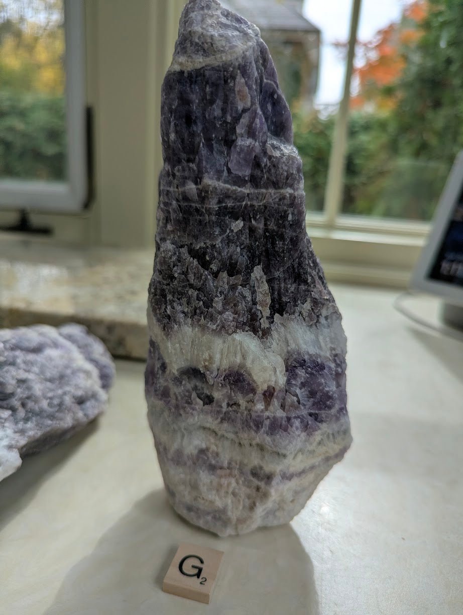 Standing raw Dream Amethyst form, showing distinct horizontal chevron layers of purple and white quartz.