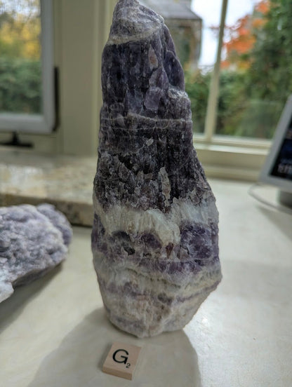 Standing raw Dream Amethyst form, showing distinct horizontal chevron layers of purple and white quartz.