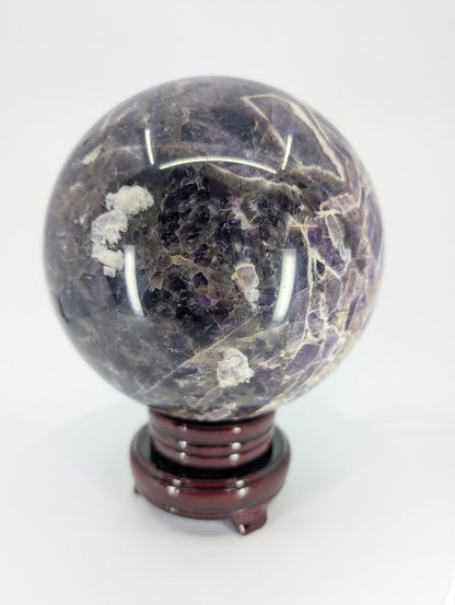 Angled close-up of Dream Amethyst sphere showing chevron pattern and translucence