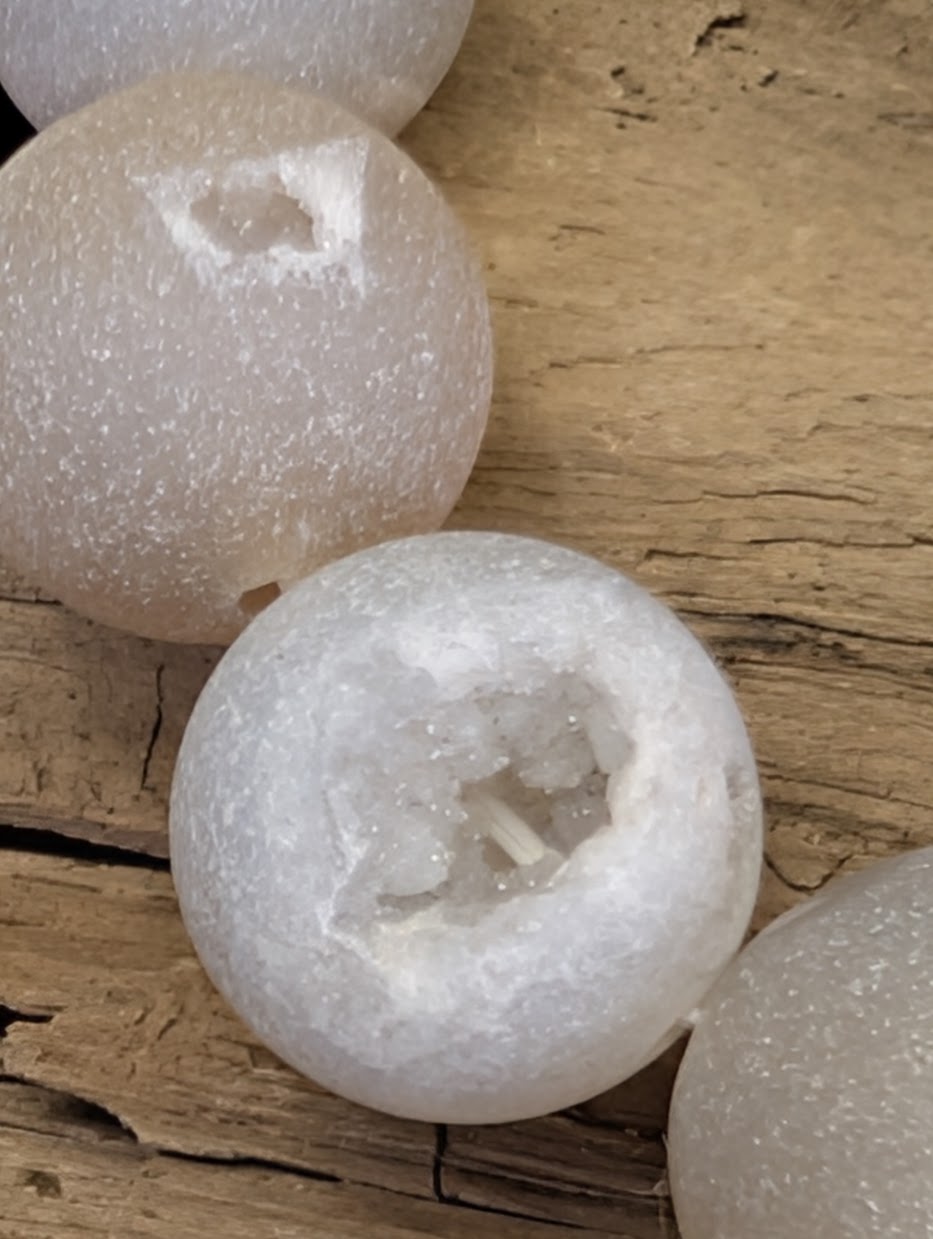 Macro shot of a natural druzy vug in a 14mm Agate bead, highlighting the tiny, glittering quartz crystals.